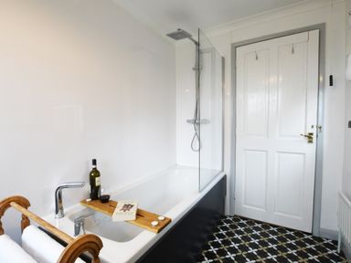 A bathroom with bathtub shower and wooden towel rack at Rosedene Rickinghall