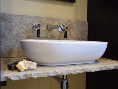 A bathroom sink with wall-mounted faucet and two bars of soap on a stone countertop at Cragside Aldeburgh