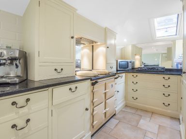 A kitchen with cream cabinets black countertops a stove microwave and a coffee machine at Skelder Parham in Parham Near Framlingham