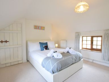 A bedroom with a bed with white and gray bedding and rolled towels on the bed at Skelder Parham in Parham Near Framlingham