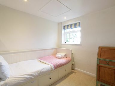 A small bedroom with a single bed next to a window and a wooden cabinet at Skelder Parham in Parham Near Framlingham