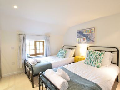 A bedroom with two single beds a window and a nightstand at Skelder Parham in Parham Near Framlingham