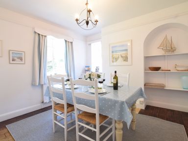 A dining room with a table set for four with a blue polka dot tablecloth and white chairs at High Ground Reydon in Reydon