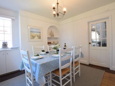 A dining room with a table covered by a blue polka dot tablecloth and six white chairs at High Ground Reydon