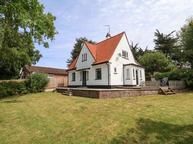 A white house with a red tiled roof and a green lawn at High Ground Reydon in Reydon