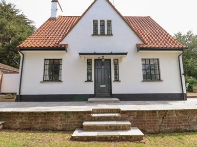 Front view of a house with a tiled roof black framed windows black door and brick steps at High Ground Reydon in Reydon