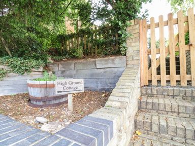 A wooden gate and stairs next to a garden area with a sign that reads High Ground Cottage at High Ground Reydon