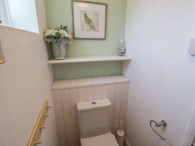 A bathroom with a toilet and shelf at High Ground, Reydon