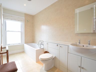 A bathroom with a bathtub toilet sink and mirror at Pier View Southwold