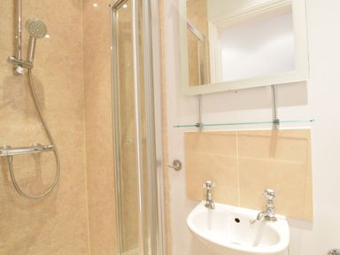 A bathroom with a shower and a sink with two taps at Pier View Southwold in Southwold
