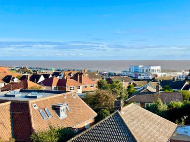 A view of rooftops and houses with the sea and a pier in the background at Pier View Southwold