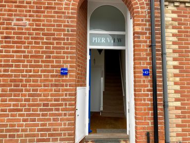 An entrance door to a brick building with the sign Pier View above and number 43 and 43a on blue plaques in Southwold