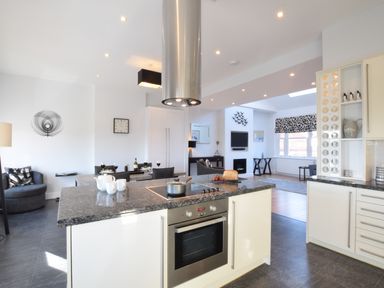 A kitchen with an island and stovetop overlooking a dining area and living room at Pier View Southwold