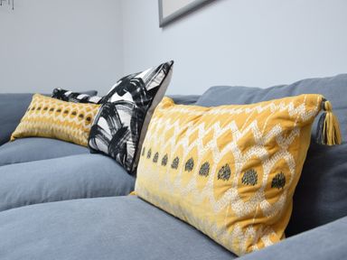 A close up of patterned yellow and black cushions on a blue sofa at Pier View Southwold
