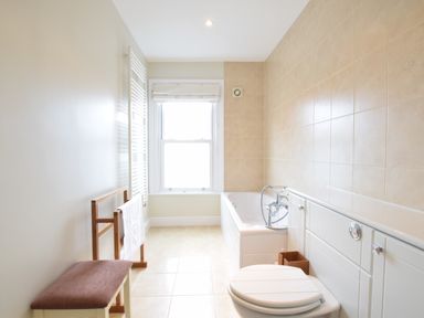 A bathroom with a bathtub toilet bench and a towel rack at Pier View Southwold