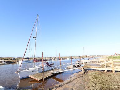 A marina with sailboats docked along wooden piers on a clear day at The Old Fisherman's Hut in Southwold