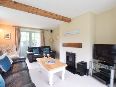 A living room with two leather sofas a wooden coffee table a fireplace and a television at Hoist Cottage Walberswick