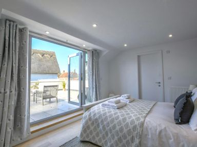 A bedroom with bed towels pillows and a door leading to an outdoor patio at Sea Green Cottage Walberswick