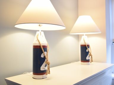 Two table lamps with white shades on a white dresser at Sea Green Cottage Walberswick