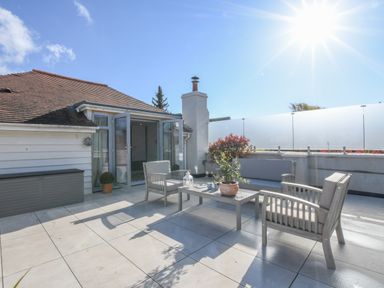 An outdoor patio area with seating including chairs and a sofa and a coffee table with a potted plant at Sea Green Cottage Walberswick