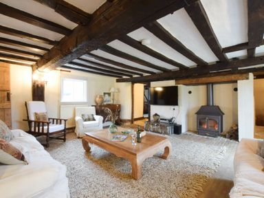 A living room with wooden beams a fireplace and furniture at Church Farmhouse Cookley Near Halesworth