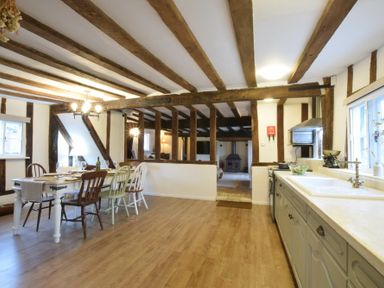 A kitchen and dining area with wooden beams and a wood floor at Church Farmhouse Cookley Near Halesworth