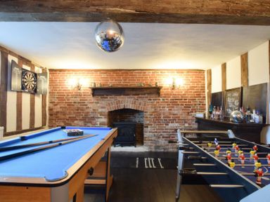 A game room with a pool table, foosball table, dartboard, and bar area at Church Farmhouse Cookley Near Halesworth