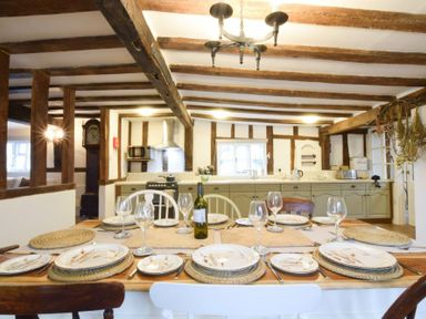 A dining area with a set table and a kitchen with wooden beams at Church Farmhouse Cookley Near Halesworth