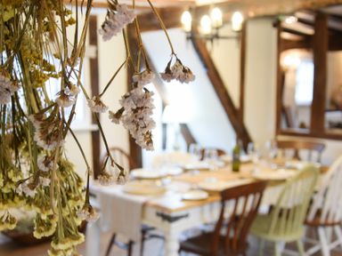 Dried flowers hanging in front of a dining table with chairs and place settings at Church Farmhouse Cookley Near Halesworth
