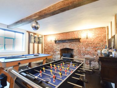 A game room with a foosball table a pool table and a dartboard on the wall at Church Farmhouse Cookley Near Halesworth
