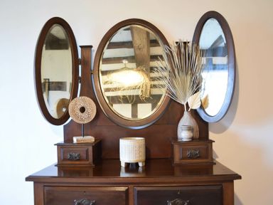 A wooden dresser with three oval mirrors and decorative items on top at Church Farmhouse Cookley Near Halesworth