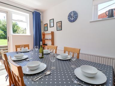 A dining area with a polka dot tablecloth set with plates bowls glasses and cutlery at Time Out Southwold in Southwold