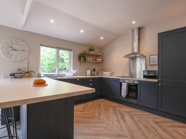 A kitchen with black cabinets wooden shelves and a window at The Piglets in Newbourne Near Woodbridge