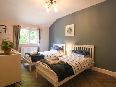 A bedroom with two single beds with striped bedding and a framed turtle picture on the wall at The Piglets in Newbourne Near Woodbridge