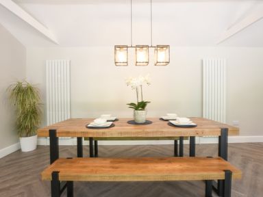 A dining room with a wooden table and bench set with plates bowls and a potted plant at The Piglets in Newbourne Near Woodbridge