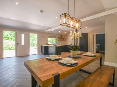 A kitchen with a wooden dining table set with plates bowls and a plant at The Piglets in Newbourne Near Woodbridge