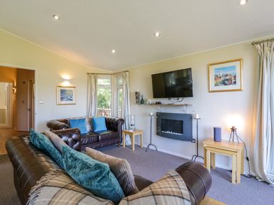 A living room with two leather sofas a wall-mounted TV and a fireplace at The Hide Out in Aldeburgh