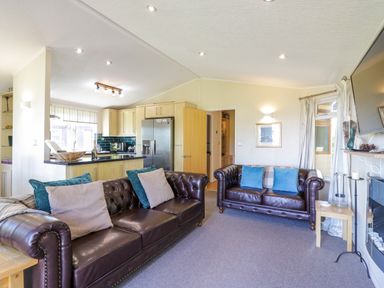 A living room with two leather sofas and a kitchen area in the background at The Hide Out Aldeburgh