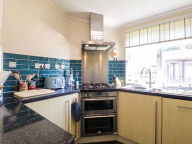 A kitchen with a stove oven range and blue tiled backsplash at The Hide Out in Aldeburgh