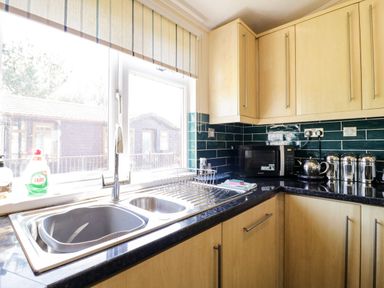 A kitchen with a double sink dish rack microwave kettle and storage containers at The Hide Out in Aldeburgh
