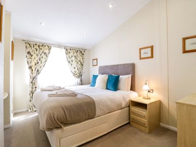 A bedroom with a double bed pillows bedside table and lamp at The Hide Out in Aldeburgh