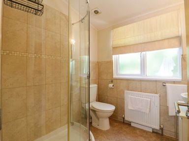 A bathroom with a shower enclosure toilet radiator and window at The Hide Out in Aldeburgh