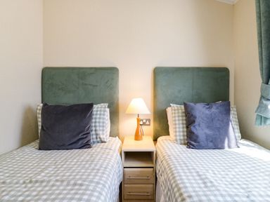 A bedroom with two single beds a nightstand and a lamp at The Hide Out Aldeburgh