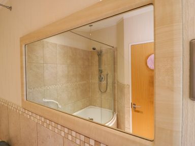 A bathroom with a bathtub shower combination tiled walls and a wooden door at The Hide Out in Aldeburgh