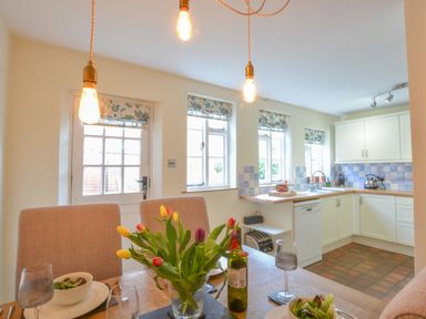 A kitchen with dining table flowers and tableware at Chapel Cottage Newbourne Near Woodbridge