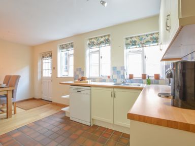 A kitchen with countertop appliances a dishwasher and dining table with chairs at Chapel Cottage Newbourne Near Woodbridge