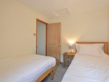 A bedroom with two single beds a wooden door and a bedside table with a lamp at Chapel Cottage Newbourne Near Woodbridge