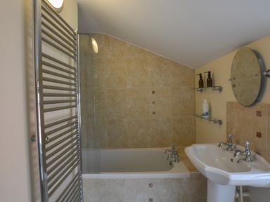 A bathroom with a bathtub shower sink mirror and towel radiator at Chapel Cottage Newbourne Near Woodbridge