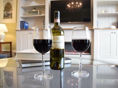 A glass table with two glasses of red wine and a bottle in a living room at Regatta Lookout in Aldeburgh
