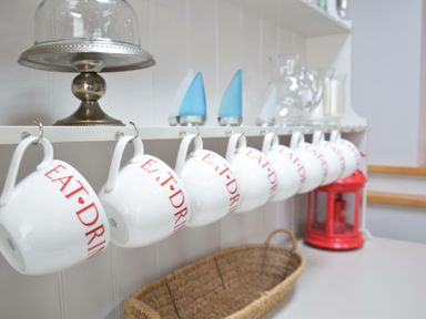 A kitchen shelf with white mugs hanging and a red lantern on the counter at Regatta Lookout in Aldeburgh